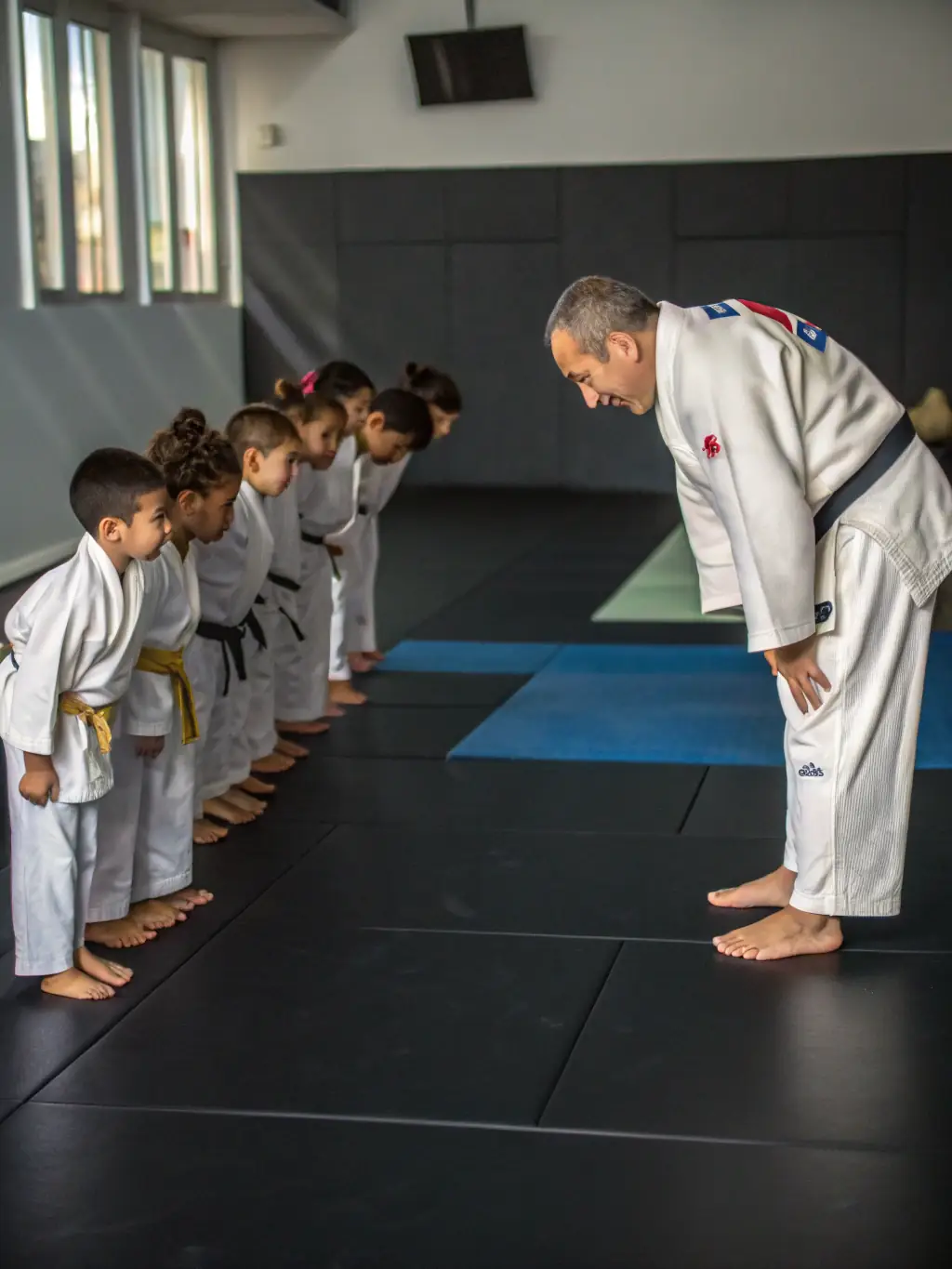 A young judoka bowing respectfully to their sensei, illustrating the emphasis on respect and discipline within the club.